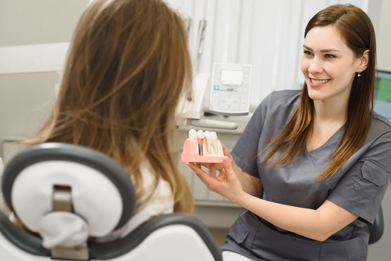 Dental Assistant Showing Off A Dental Implant Model